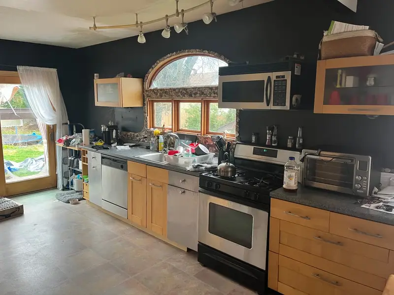 Occupied kitchen with an arched window and crowded counters, Islip, NY